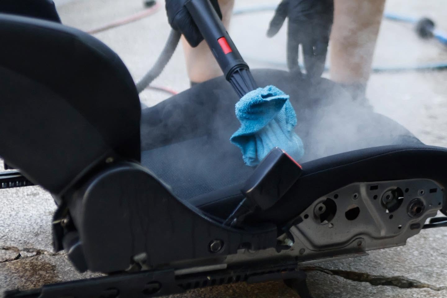 Steam cleaning a removed seat during interior car detailing