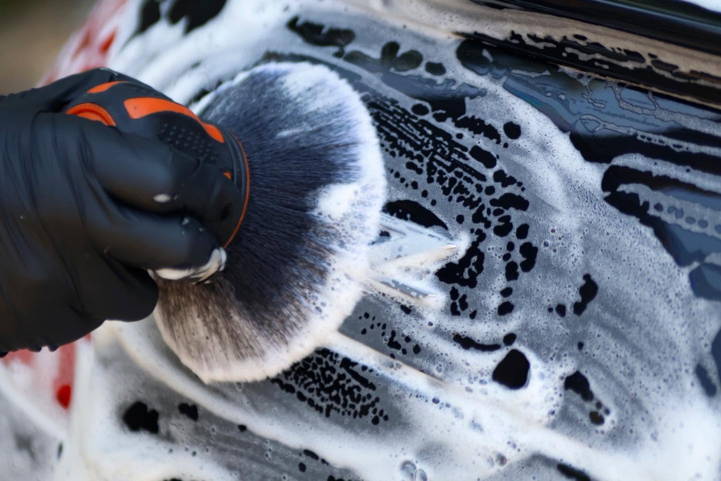Detail brush cleaning a foamed emblem during exterior detailing